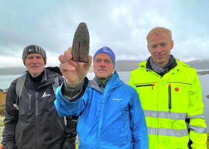 Reidar Marstein (i midten) holder stokken som er 7000 år gammel. Trygve Hesthagen står til venstre og Axel  Mjærum fra Kulturhistorisk museum til høyre i foto.  - Klikk for stort bilde
