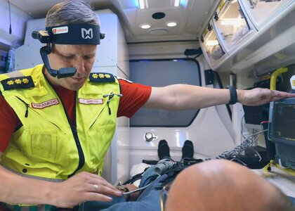 Ambulansearbeider med pasient i ambulansen snakker med lege på videolink - Klikk for stort bilde