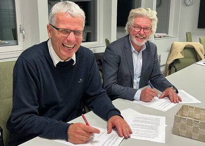 To menn smiler mens de signerer avtalen mellom NAV og Innlandet fylkeskommune - Klikk for stort bilde