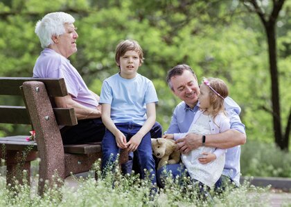 Bestefar, far og to barnebarn på en benk i en park - Klikk for stort bilde