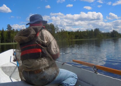 Mann som fisker fra båt i en innsjø  - Klikk for stort bilde